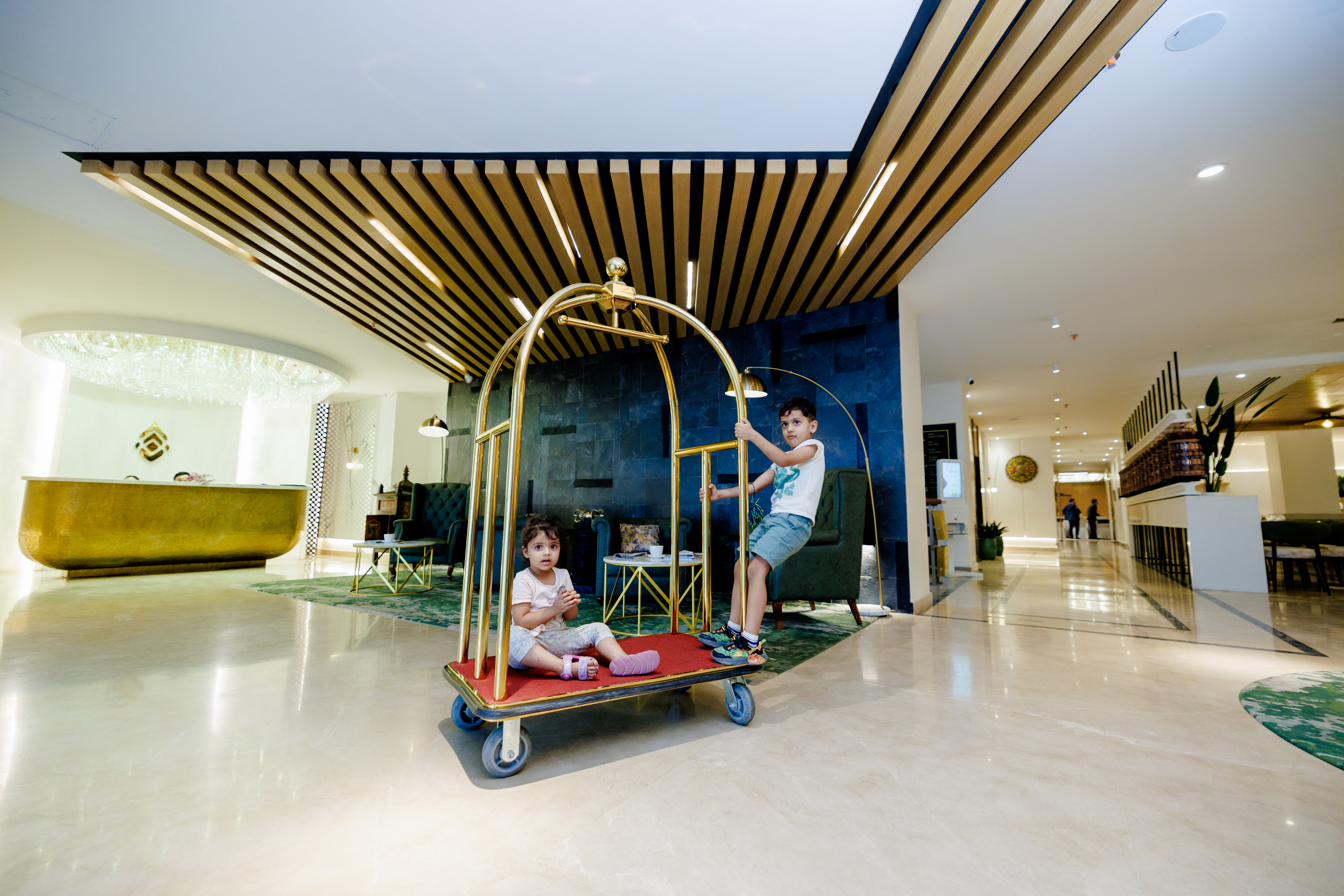 A child playing on a brass luggage trolley in the lobby